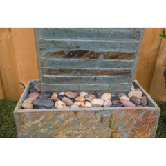 Natural Stone Floor Fountain with Light Rectangular Base Supports The water Wall, with River Stones Resting on The Bottom